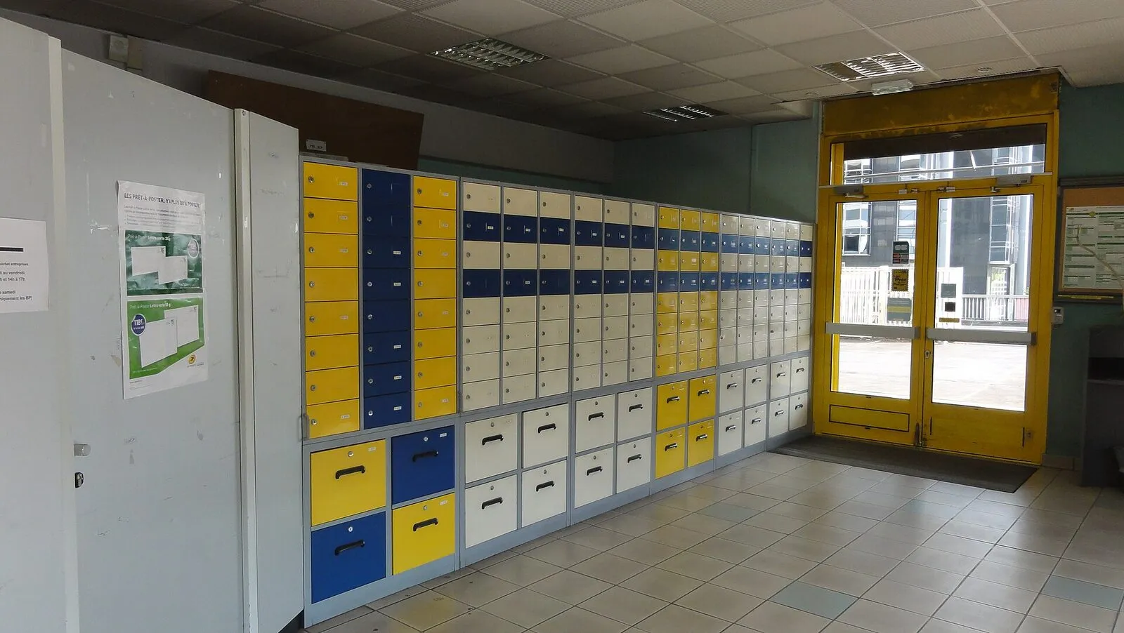 A long bank of numbered post office boxes running down an empty sorting room